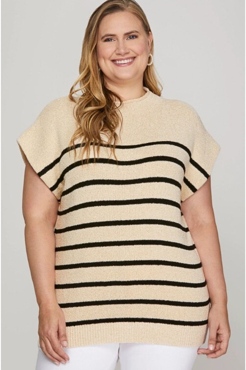 Woman wearing a beige and black striped sweater against a plain background