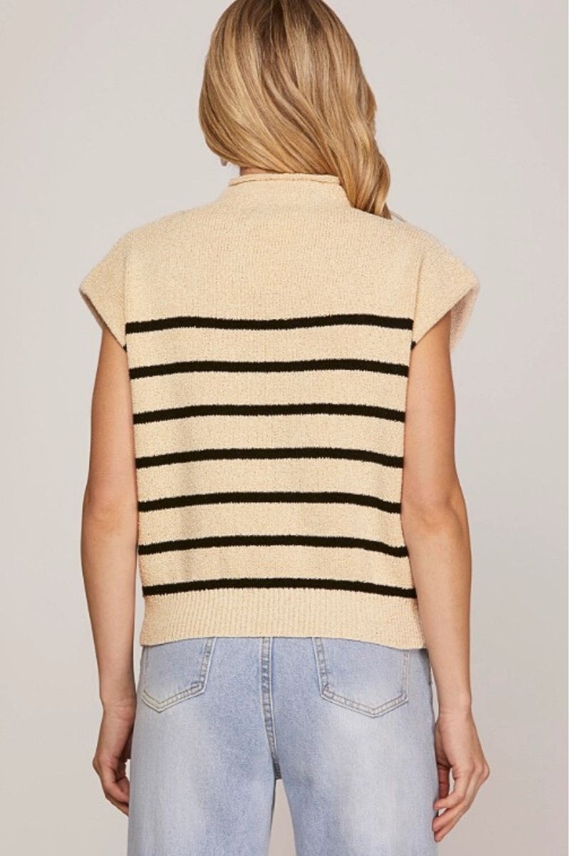 Beige sleeveless sweater with black stripes worn by a person on a plain background
