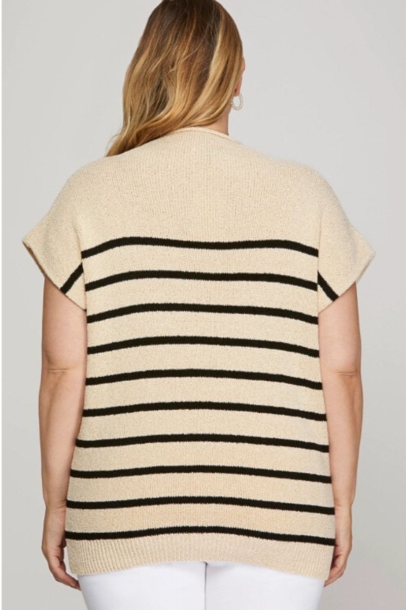 Beige sweater with black stripes worn by a person on a plain background