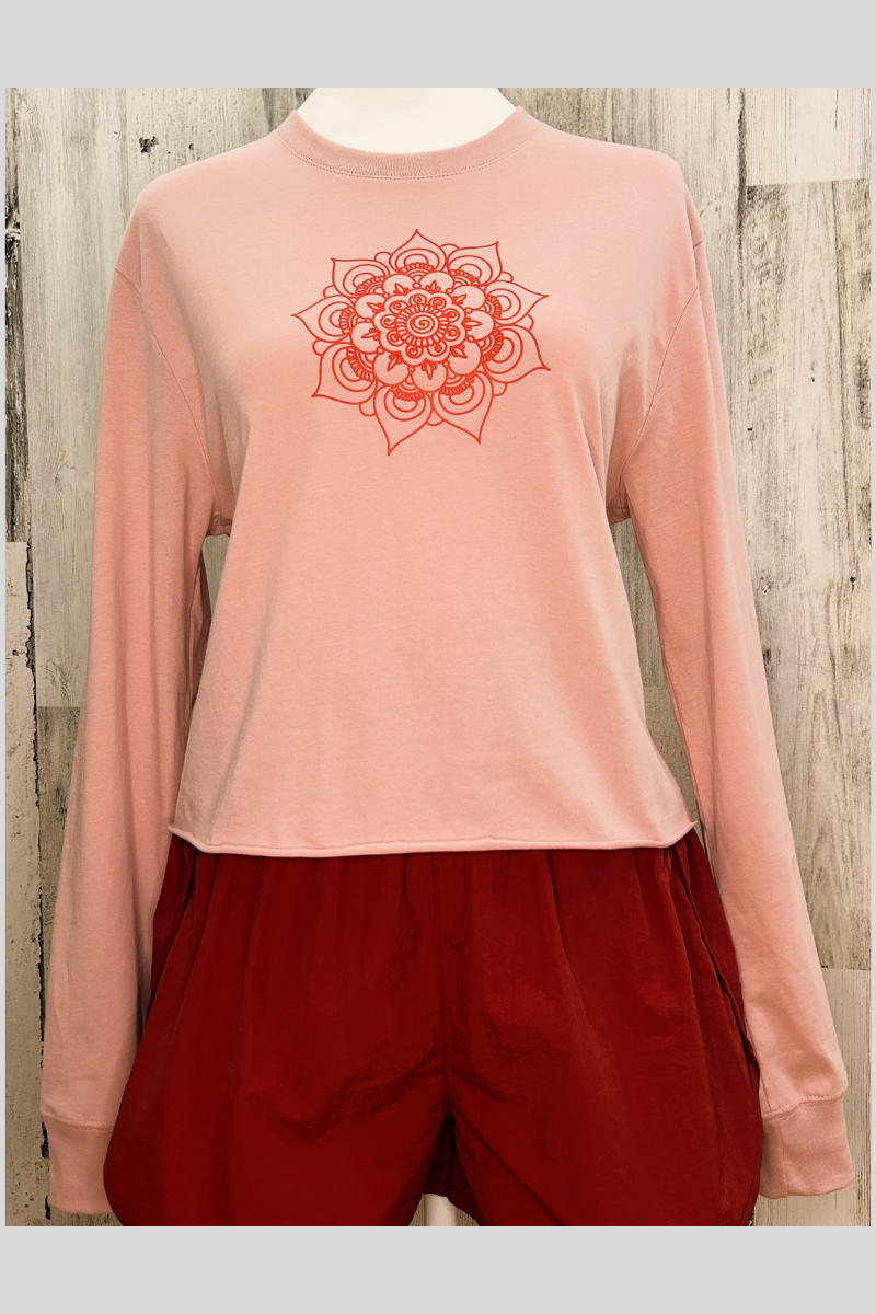 Sustainable long sleeve crop tee in pink with a raw edge bottom and mandala design