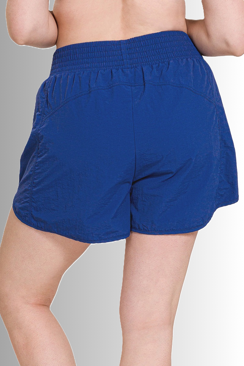 Zenana sustainable sport shorts with side zip pocket in light navy, smocked waistband, windbreaker material