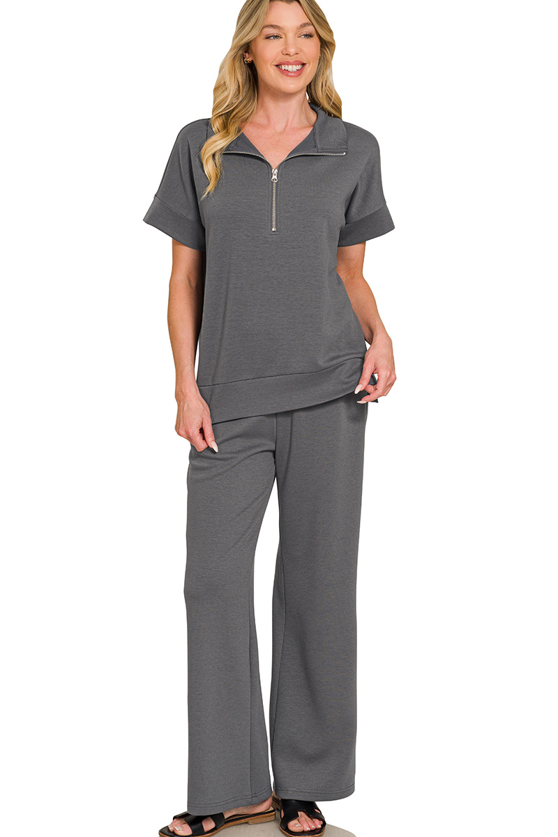 Woman wearing a gray zip-up top and pants set on a white background
