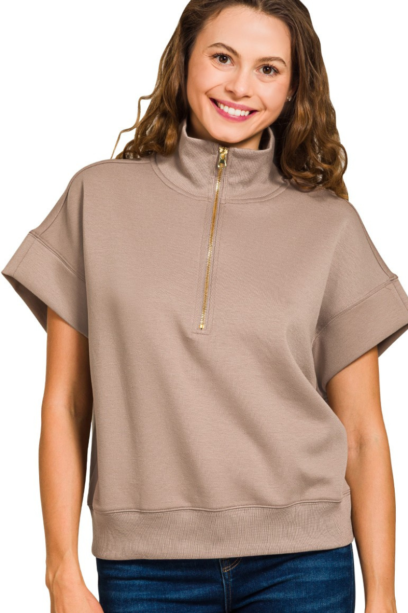 Woman wearing a beige short-sleeve top with a zipper on a white background