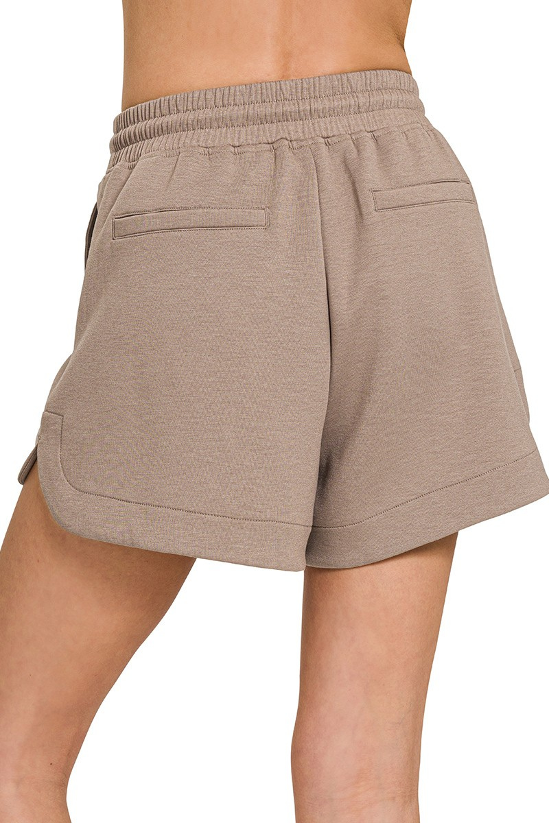 Beige shorts worn by a person on a white background