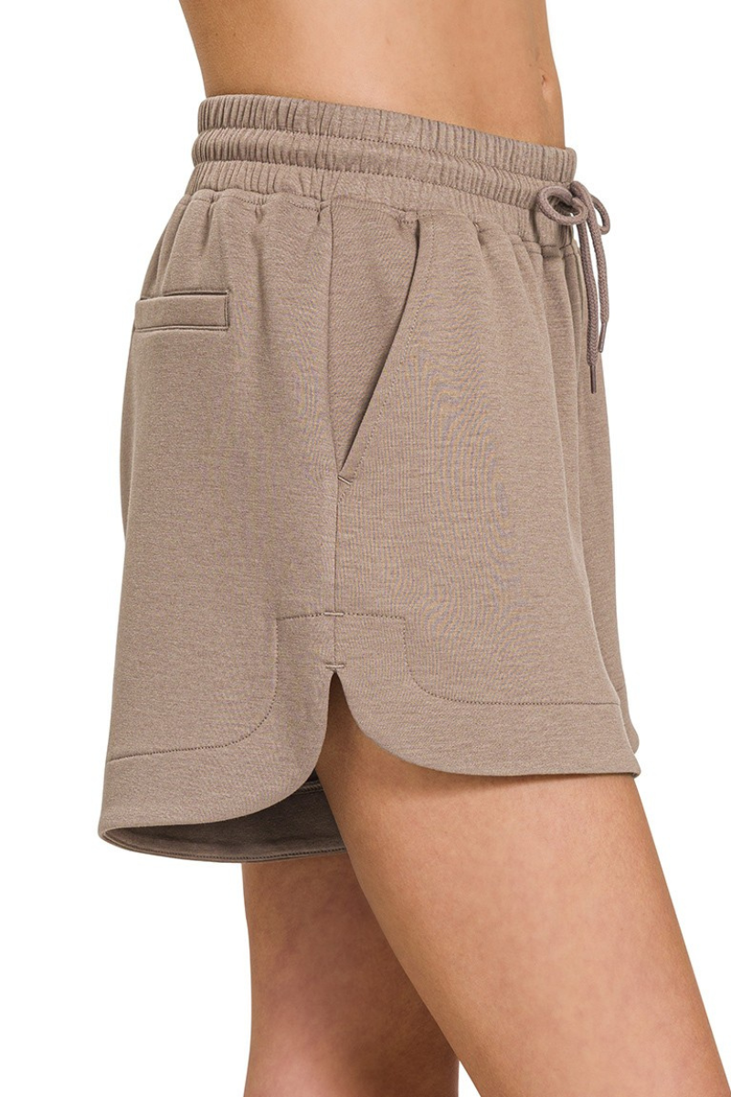 Beige shorts worn by a person on a white background