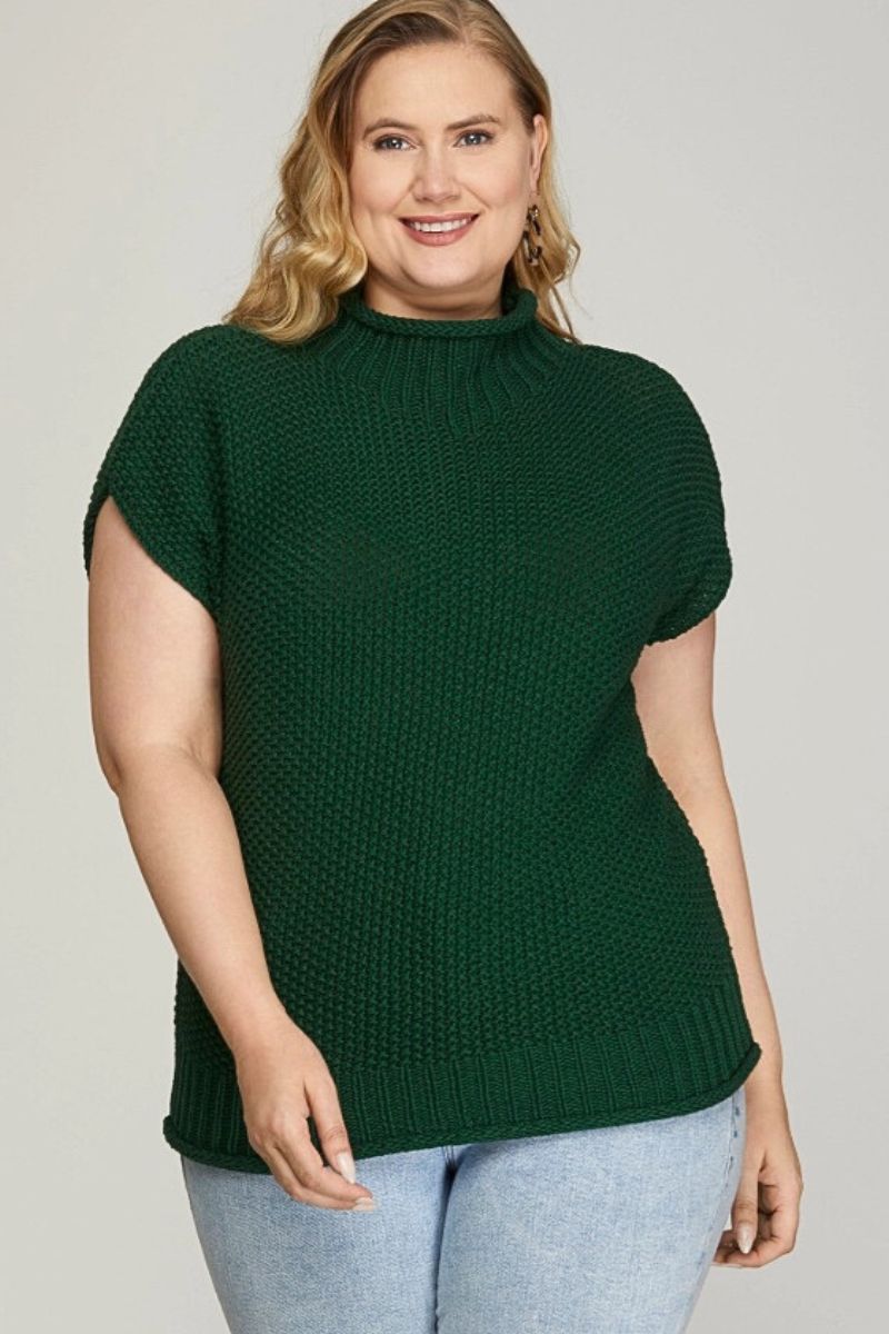 Woman wearing a green knitted sweater on a plain background