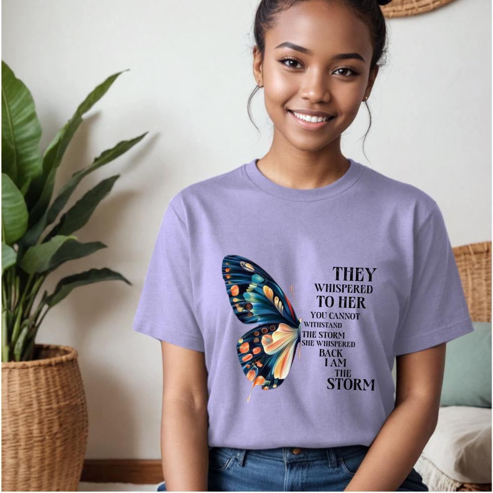 Person wearing a purple t-shirt with a butterfly graphic and text, sitting indoors.