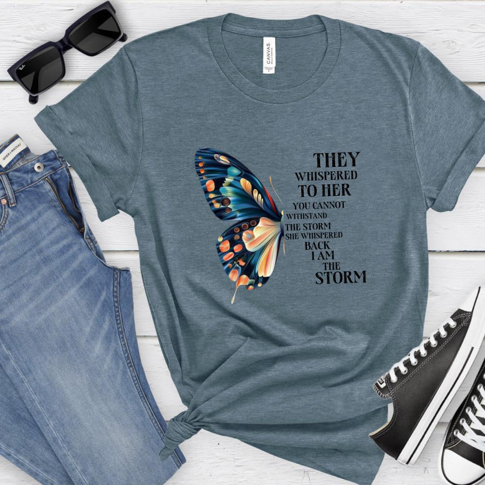 Blue t-shirt with butterfly design and text, paired with jeans and sneakers on a wooden surface.