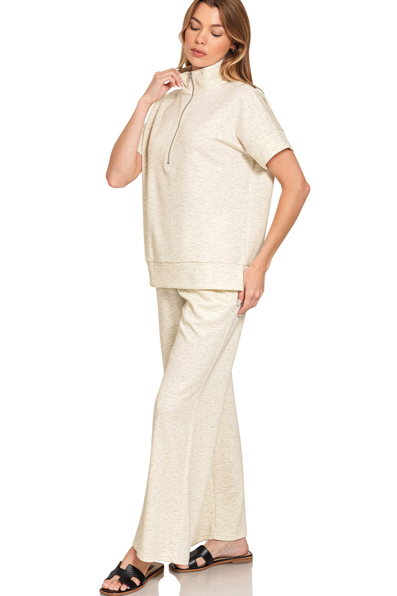 Woman wearing a beige outfit with a matching top and pants on a white background