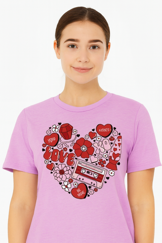 Person wearing a pink t-shirt with a heart-shaped design featuring red hearts, flowers, and a cassette tape.