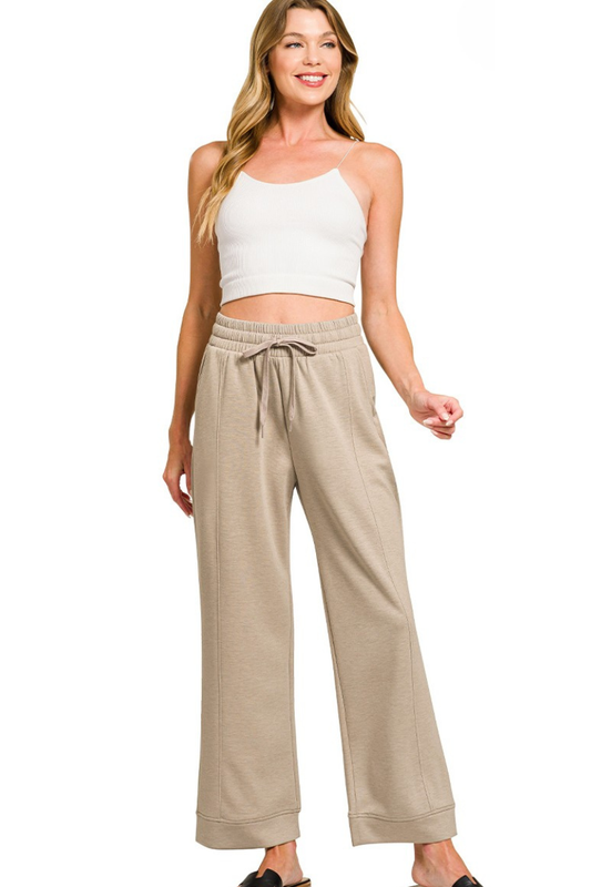 Woman wearing a white top and beige pants on a white background