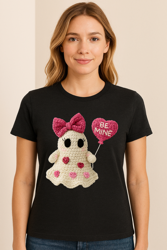 Woman wearing a black t-shirt with a crochet ghost design holding a 'Be Mine' balloon.